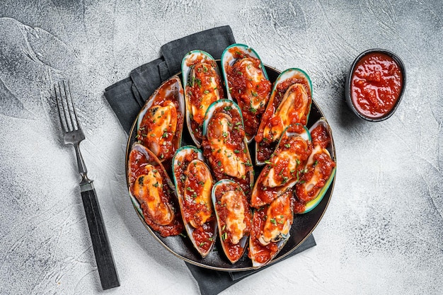 Grandi cozze verdi cotte in salsa di pomodoro con aglio prezzemolo e limone Sfondo bianco Vista dall'alto