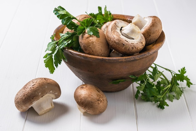 Grandi funghi reali in una ciotola di argilla profonda su un tavolo bianco. Cibo vegetariano. Funghi coltivati artificialmente.