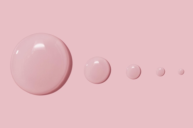 Grandi gocce di gel d'acqua liquido siero cosmetico su sfondo rosa