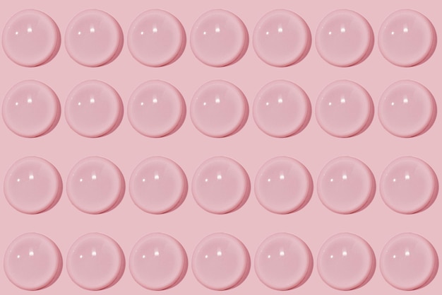 Grandi gocce di siero cosmetico di gel d'acqua liquido su sfondo rosa