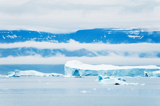 Grandi iceberg nell'Oceano Atlantico e montagne con nuvole. Villaggio di Saqqaq, Groenlandia occidentale.