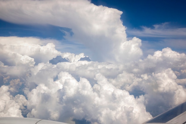 Grandi nuvole bianche leggere su uno sfondo di cielo blu. Vista dalla finestra dell'aereo in una giornata di sole, copia dello spazio. Concetto di viaggio e trasporto.