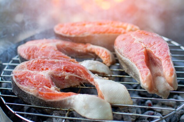 Grandi pezzi di pesce rosso si trovano sulla griglia, barbecue al salmone, primo piano