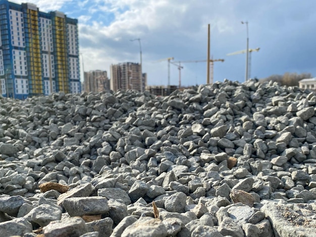 Grandi pietre grigie macerie dalla costruzione di strade industriali e una vista di nuovi edifici