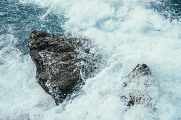 Grandi pietre in acque azzurre del primo piano del fiume di montagna.