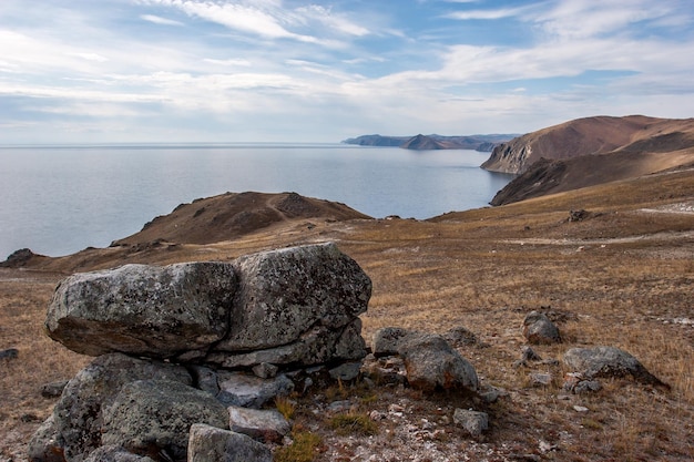 Grandi pietre sulla riva del lago Baikal Alta costa rocciosa Ci sono nuvole nel cielo blu Il lago è calmo