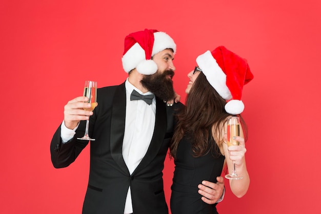 Grandi relazioni amorose iniziano con lo champagne Coppia innamorata in abiti da cerimonia con look da Babbo Natale Brindisi per amare La famiglia felice festeggia il nuovo anno e il Natale Adoriamo la vigilia di Natale