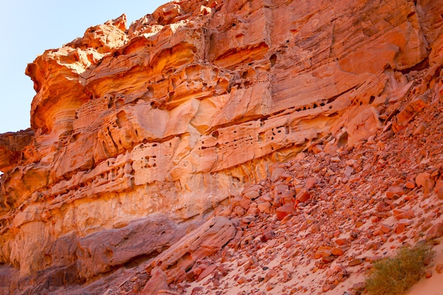 Grandi rocce di roccia in un canyon rosso attraverso il quale i raggi di luce si infrangono contro il cielo blu