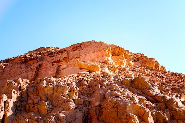 Grandi rocce di roccia in un canyon rosso attraverso il quale i raggi di luce si infrangono contro il cielo blu