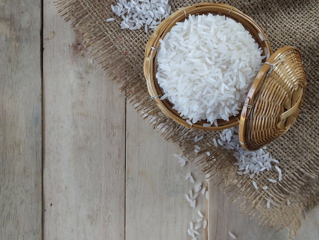 Grani del riso bianco sul fondo di legno della tavola e della tavola