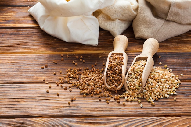 Grani di grano saraceno verdi e fritti nelle palette di legno sul tavolo di legno. Pseudocereali senza glutine