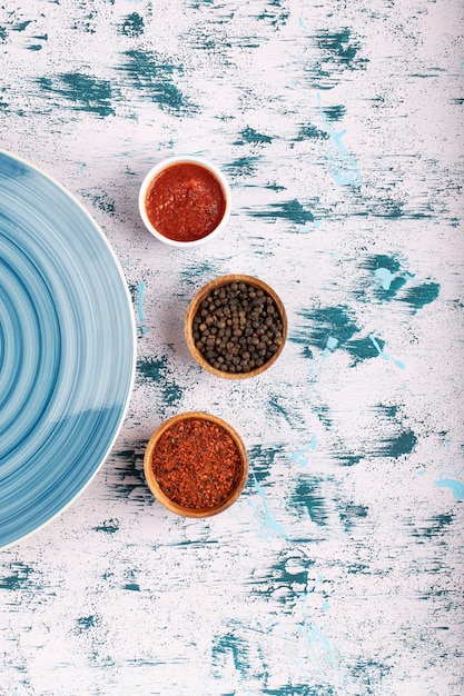 Grani di pepe con polvere e piatto blu posto sul tavolo di pietra.