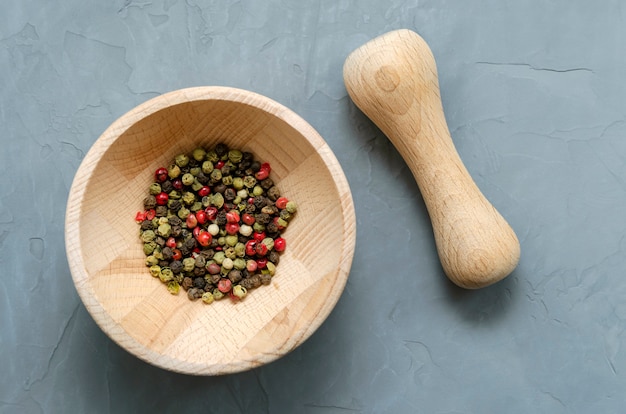 Grani di pepe nero verde rosso multicolore in un mortaio di legno