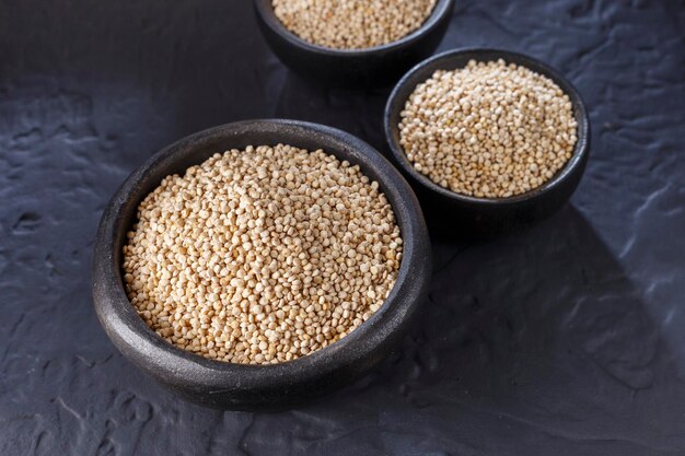 Grani di quinoa con cucchiaio e ciotola su sfondo nero