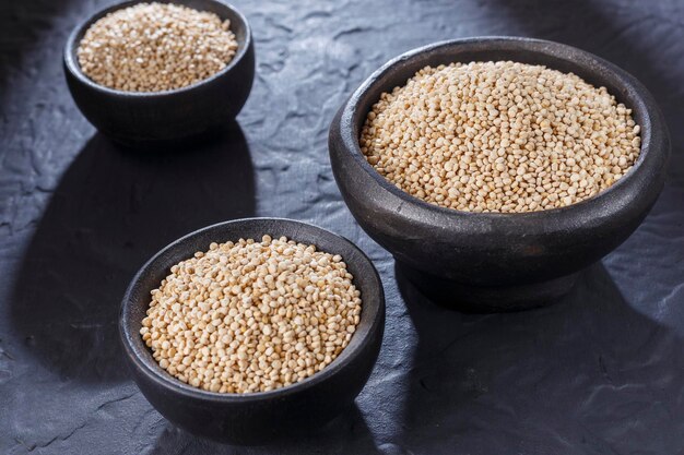 Grani di quinoa con cucchiaio e ciotola su sfondo nero