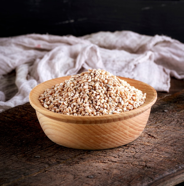 Grano del grano in una ciotola di legno su un tavolo marrone