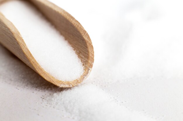 Grano di sale in cucchiaio di legno su sfondo bianco