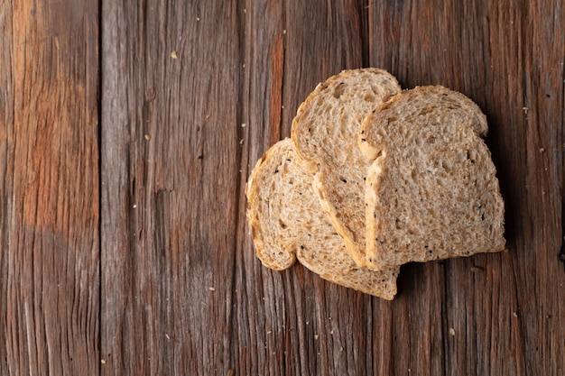 Grano intero, pane dei grani interi sul bordo di legno scuro, fine su, vista superiore