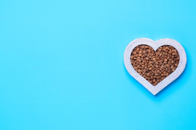 Grano saraceno a forma di cuore su sfondo blu. Cuore d'argento. Copia-spazio