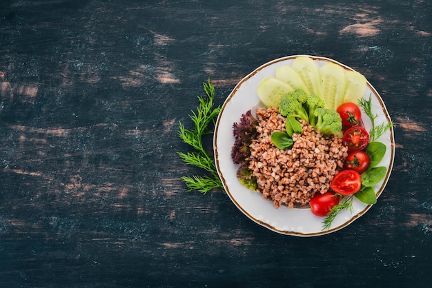 Grano saraceno con cetriolo broccoli e pomodori su uno sfondo di legno Vista dall'alto Copia spazio