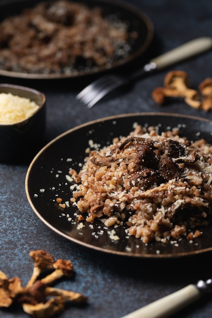 Grano saraceno cotto con funghi secchi su un piatto cosparso di parmigiano.