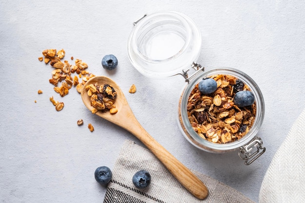 Granola al forno fatta in casa con noci e mirtilli freschi in un barattolo su sfondo chiaro primo piano Muesli vegetariano sano per colazione