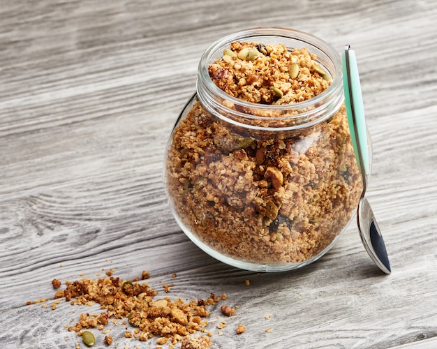 Granola casalingo in un barattolo di vetro su una tavola di legno