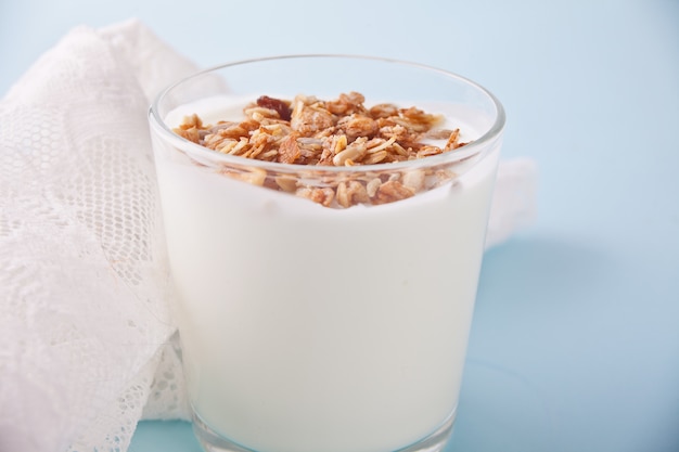 Granola con yogurt in vetro con un cucchiaio di legno su un tavolo.