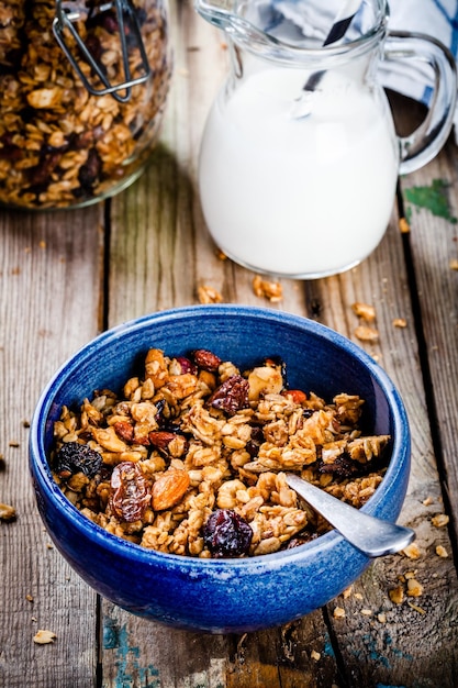 Granola fatta in casa per la colazione con uvetta e noci sulla tavola di legno