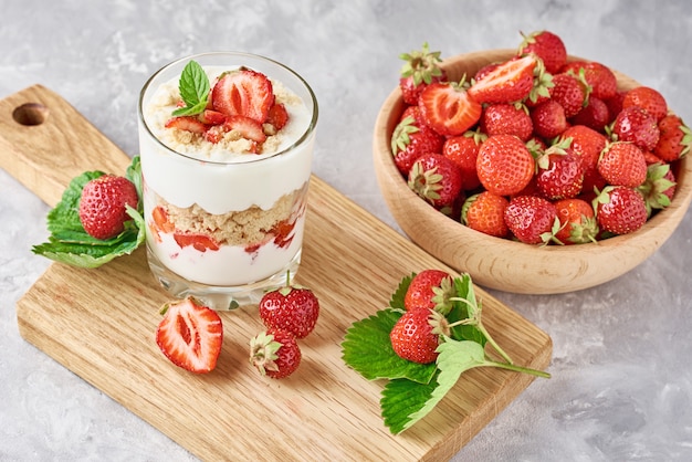 Granola o frullato di fragole in un bicchiere e bacche fresche in ciotola di legno, vista dall'alto. Colazione salutare