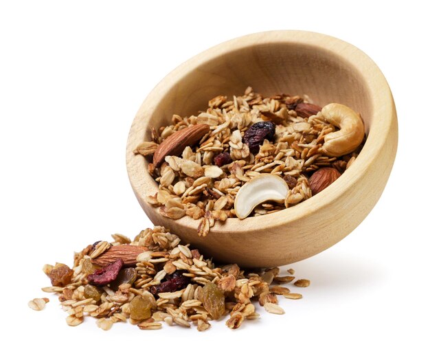 Granola versata da un piatto di legno su uno sfondo bianco Muesli isolato