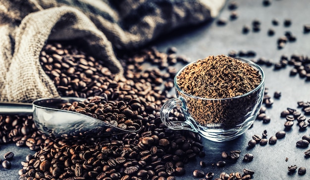 Granuli di caffè istantaneo in tazza di vetro e chicchi di caffè.