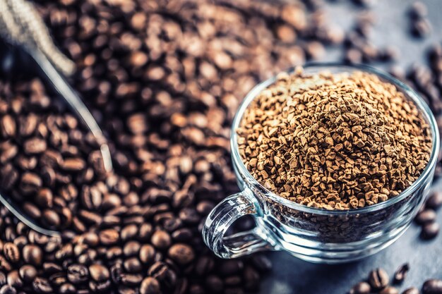 Granuli di caffè istantaneo in tazza di vetro e chicchi di caffè.