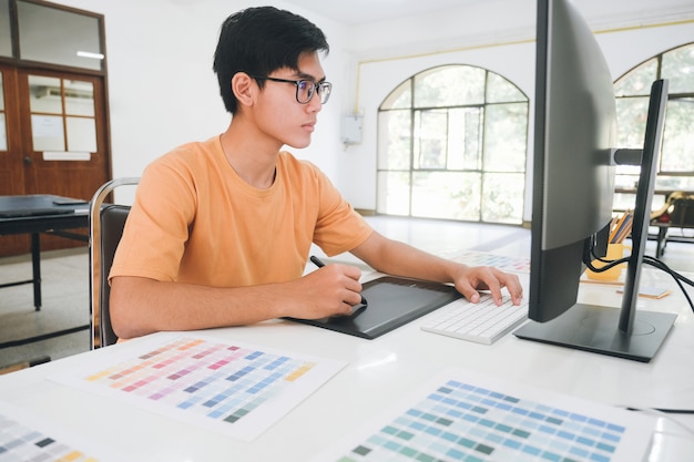 Graphic designer che lavora con campioni di colore per la selezione. Grafico pubblicitario al lavoro. Campioni di campioni di colore. Giovane fotografo e grafico al lavoro in ufficio.