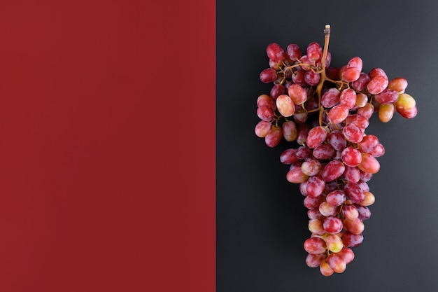 Grappolo di uva rosa su uno sfondo geometrico di vino rosso e nero a doppio colore, vista dall'alto