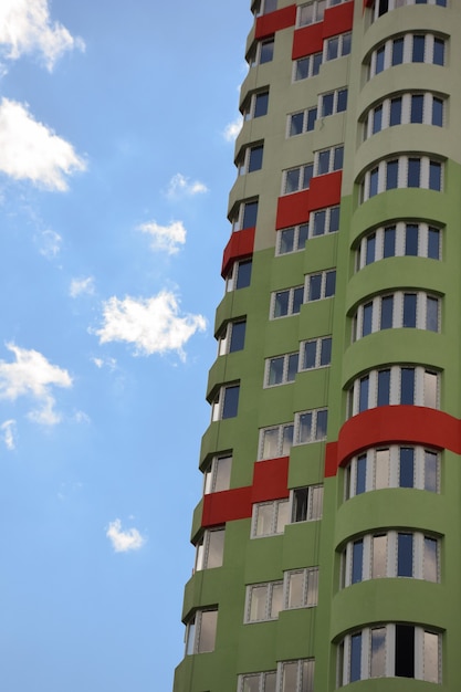Grattacielo con parete personalizzata curva e balconi contro il cielo blu. Sulla sinistra c'è un posto per inserire il testo
