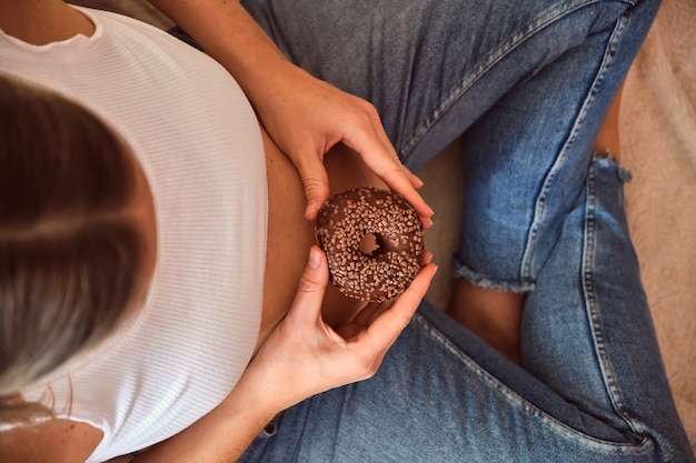 Gravidanza e nutrizione. Donna incinta che gode di ciambella e caffè, ripresa dall'alto. Concetto di aspettativa e salute.