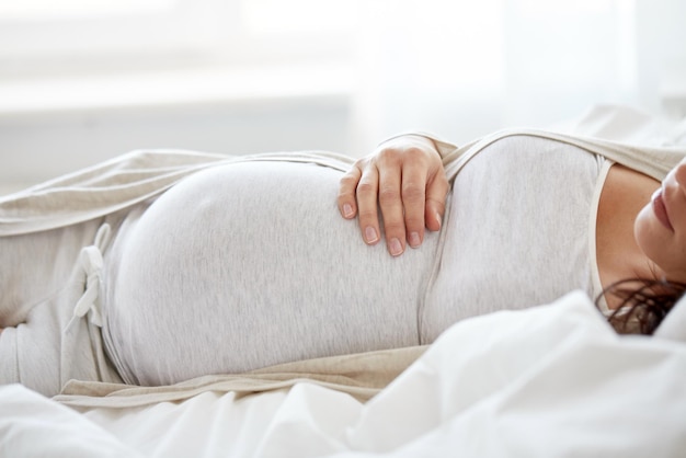 gravidanza, riposo, persone e concetto di aspettativa - donna incinta che dorme a letto a casa