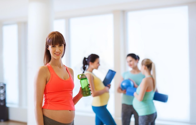 gravidanza, sport, fitness, persone e concetto di stile di vita sano - felice donna incinta con bottiglia d'acqua in palestra