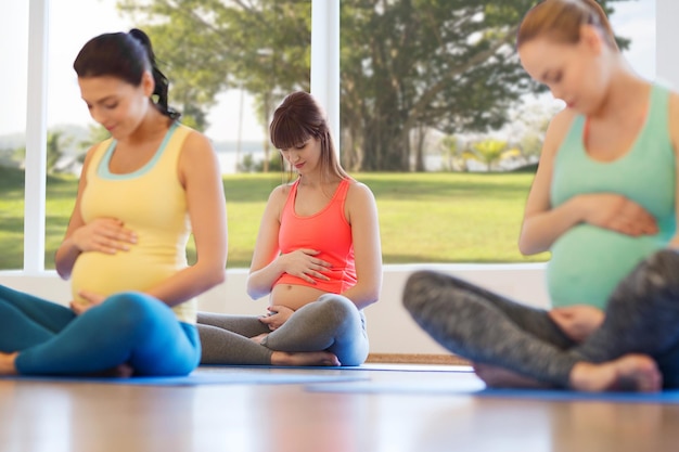 gravidanza, sport, fitness, persone e concetto di stile di vita sano - gruppo di donne incinte felici che esercitano yoga nella posa del loto in palestra
