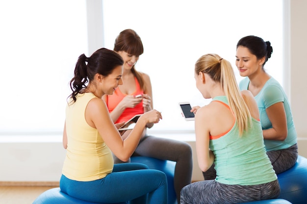 gravidanza, sport, fitness, persone e concetto di stile di vita sano - gruppo di donne incinte felici con computer tablet pc e smartphone seduti sulle palle in palestra