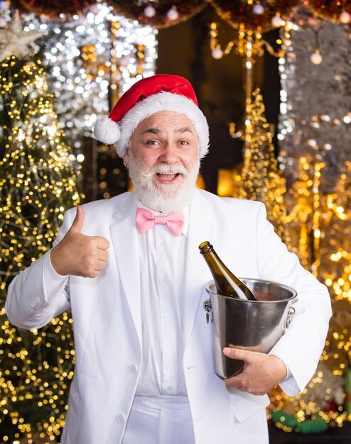 Grazie smoking senior sommelier la notte di capodanno potrebbe essere lunga buon natale a te festeggiamo l'uomo allegro tieni il secchiello del ghiaccio con una bottiglia di champagne applausi offri del buon vino freddo