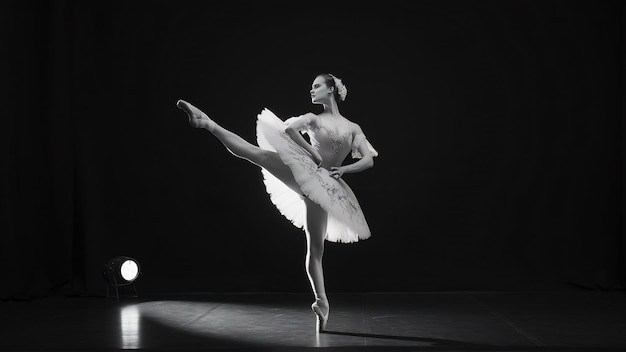 Graziosa ballerina classica isolata in uno studio nero.