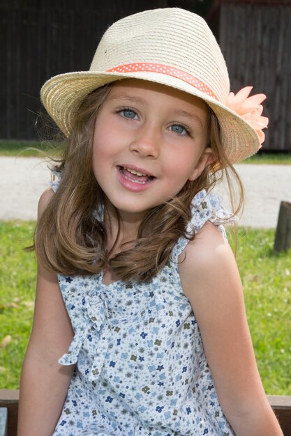 Graziosa bambina bionda con un cappello di paglia che canta all'aperto