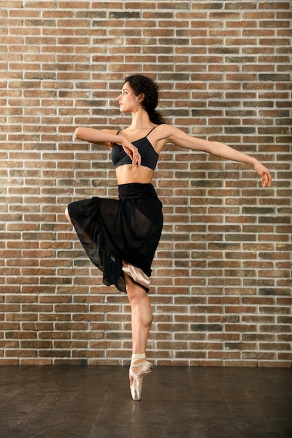 Graziosa giovane ballerina che prova in uno studio