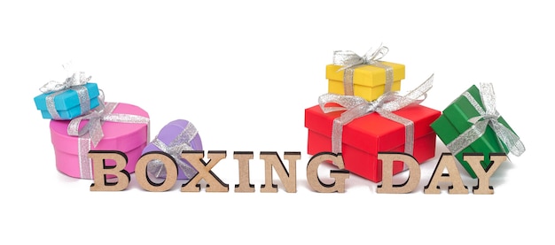 Graziose scatole regalo colorate con parole BOXING DAY, isolate su bianco