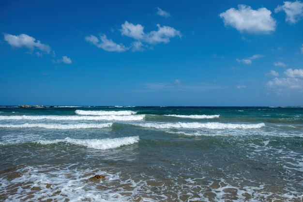 Grecia acqua di mare ondulata spruzzante schiuma cielo blu con sfondo nuvoloso spazio di copia modello di annuncio