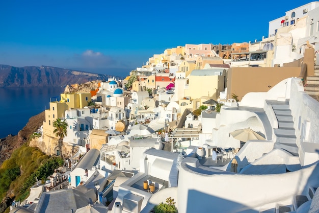 Grecia. Giornata di sole estivo a Santorini. Vista mare e edifici e terrazze di Oia con fiori sulla caldera