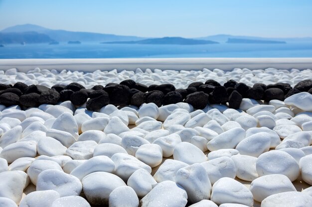 Grecia. Santorini. Isola di Thira. Pietre bianche e nere sulla terrazza con vista mare