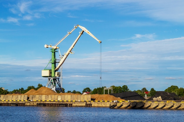 Green cargo gru nel terminale nel porto di navi fluviali a Ventspils, Lettonia, Mar Baltico. Importazione di spedizione